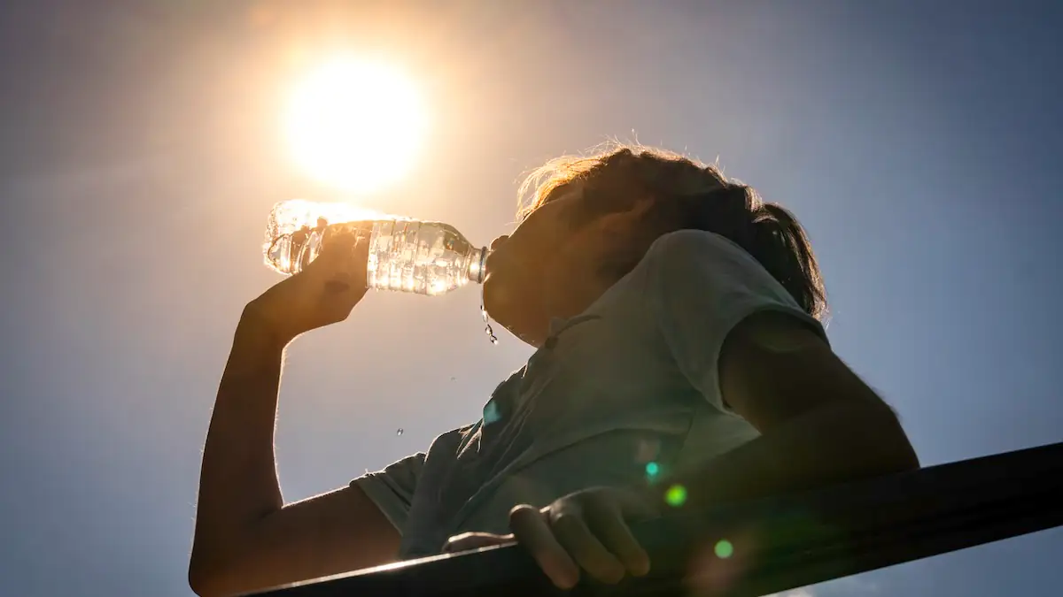 Jahrhundertsommer Symbolbild: Junge trinkt Wasser aus einer Flasche an einem sonnigen, heißen Tag