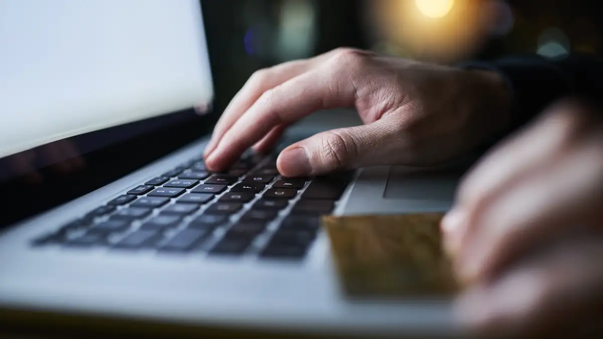 Symbolbild DHL-Betrug: Hände, Laptop- und Kreditkarte