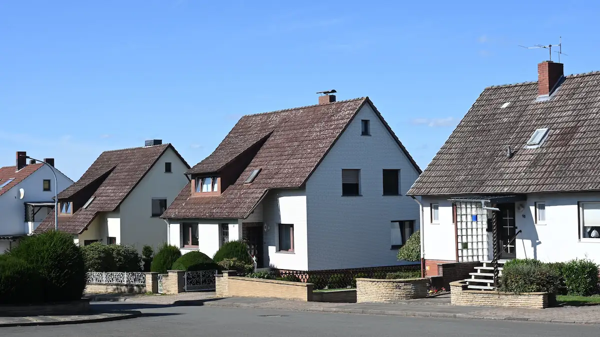 Grundsteuer Symbolbild: eine Reihe weißer Einfamilienhäuser vor blauem Himmel