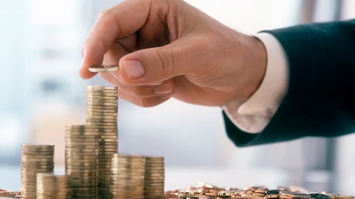 Gehalt: männliche Hand legt Euromünzen auf einen hohen Stapel