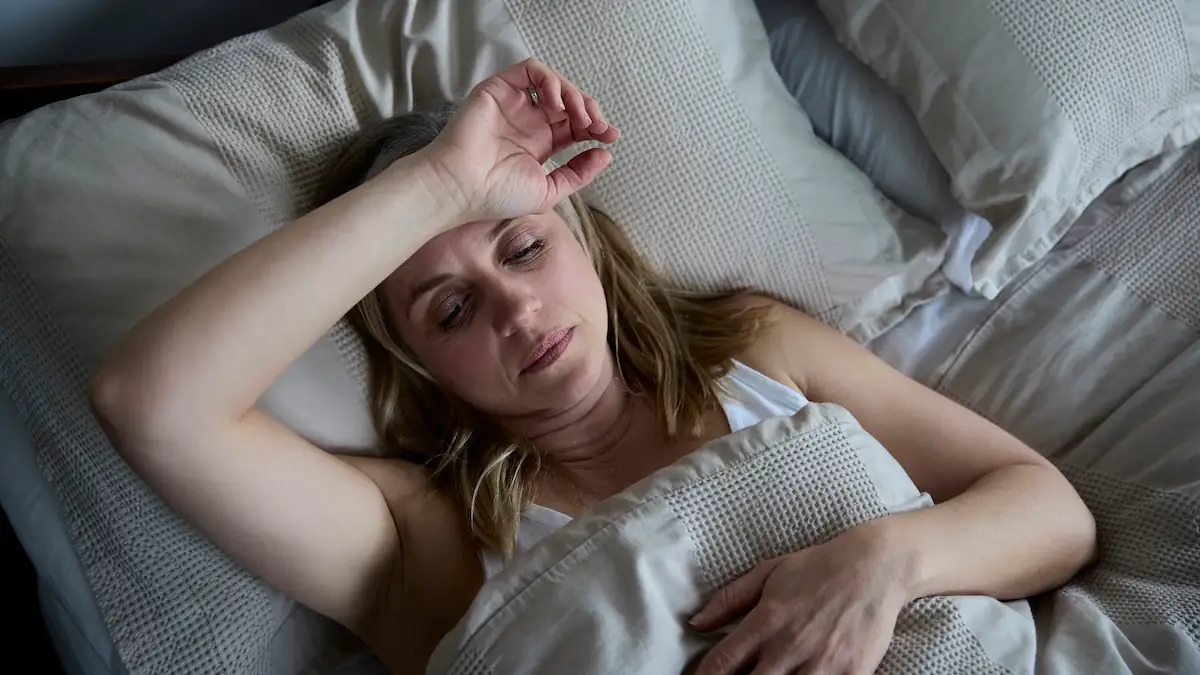Frau liegt mit Nachtschweiß im Bett
