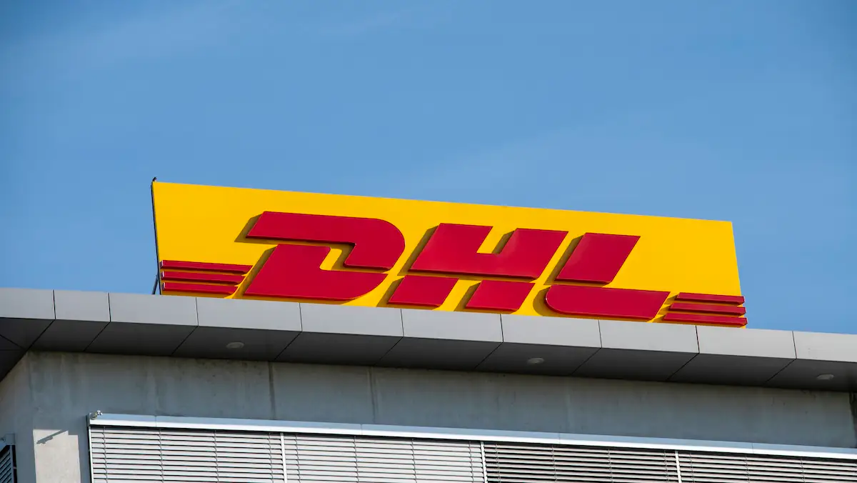 DHL-Logo auf einem Schild auf einem Gebäude vor blauem Himmel