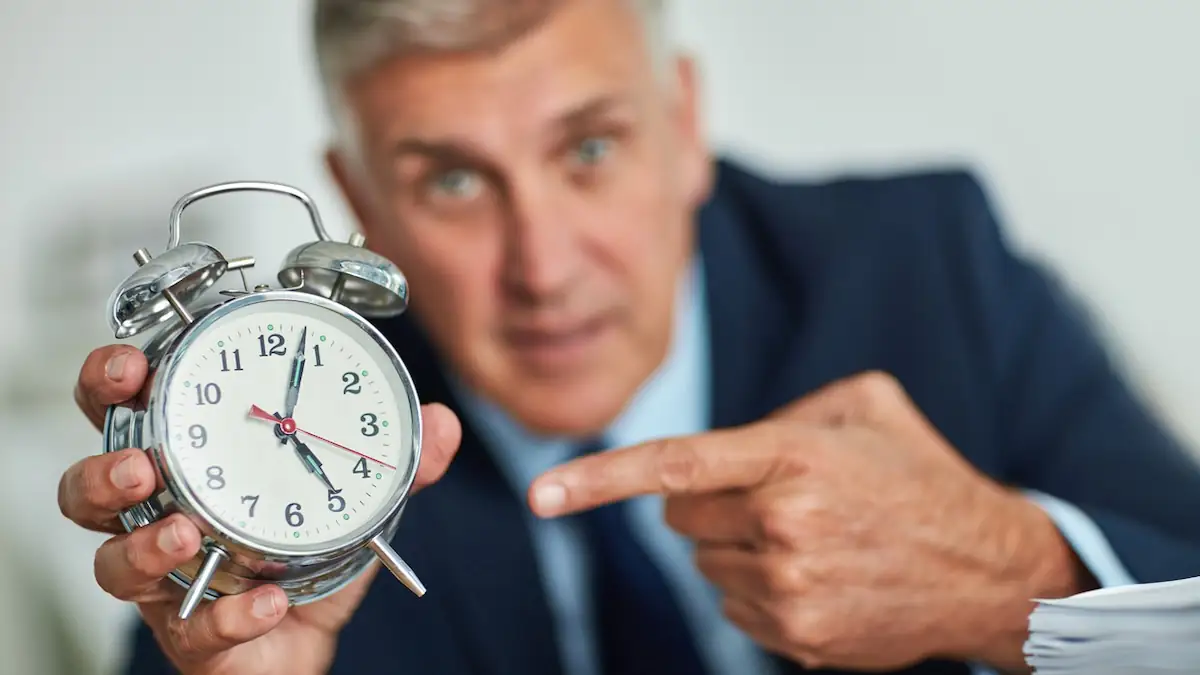 Abmahnung: Businessmann zeigt ungeduldig auf eine Uhr