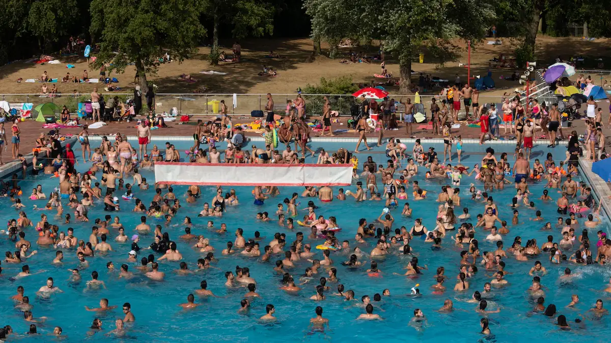 Müll in Freibädern: Ein überfülltes Freibadbecken neben einer Wiese