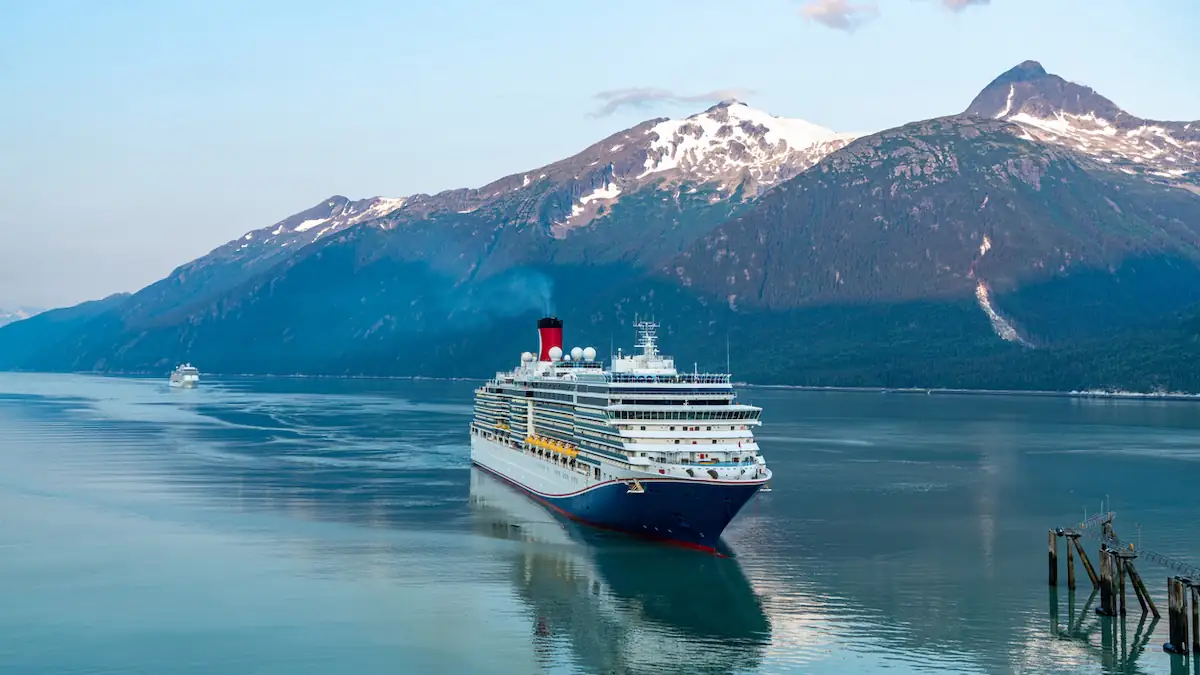 Kreuzfahrtschiff vor bergiger Kulisse auf dem Wasser