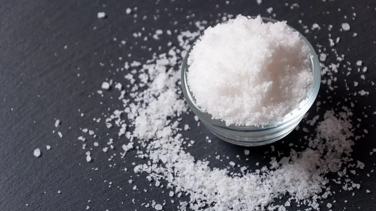 Kleine Schüssel mit Salz, das teilweise herausfällt