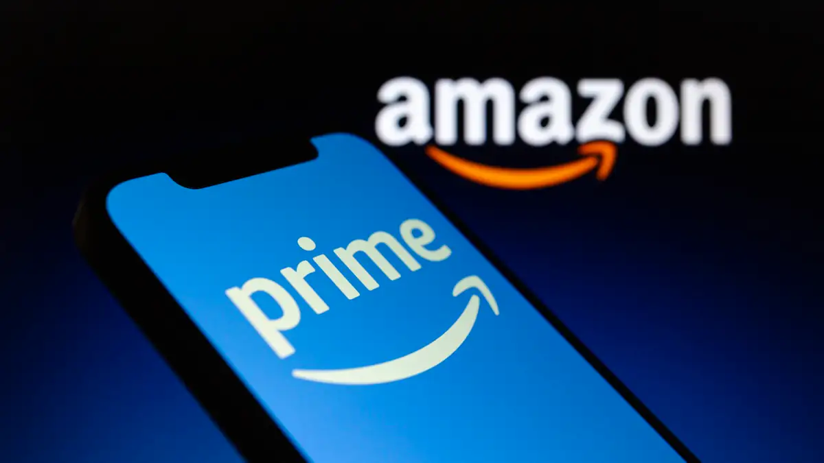 Amazon Logo im Hintergrund, davor das Prime-Logo auf einem Smartphone