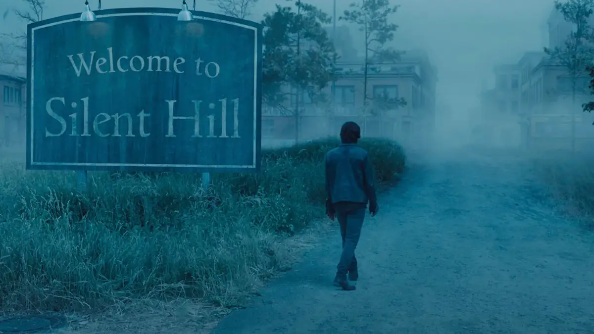 Szene aus dem Trailer zu „Return to Silent Hill“: Mann läuft auf nebliges Anwesen zu, an einem Schild vorbei, auf dem „Welcome to Silent Hill“ steht