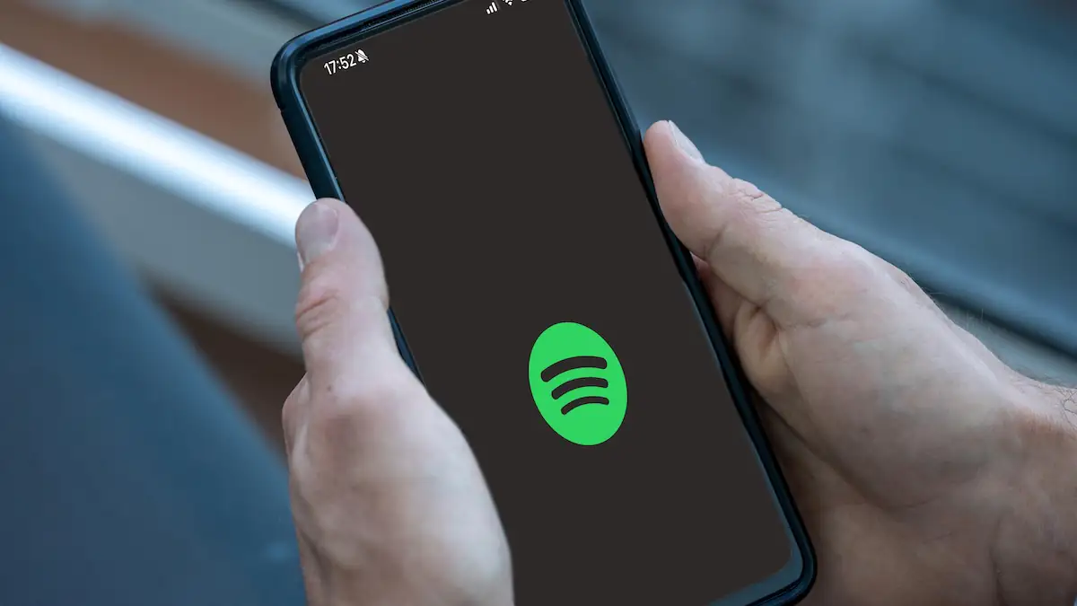 Spotify App Logo auf einem Smartphone, das jemand in der Hand hält