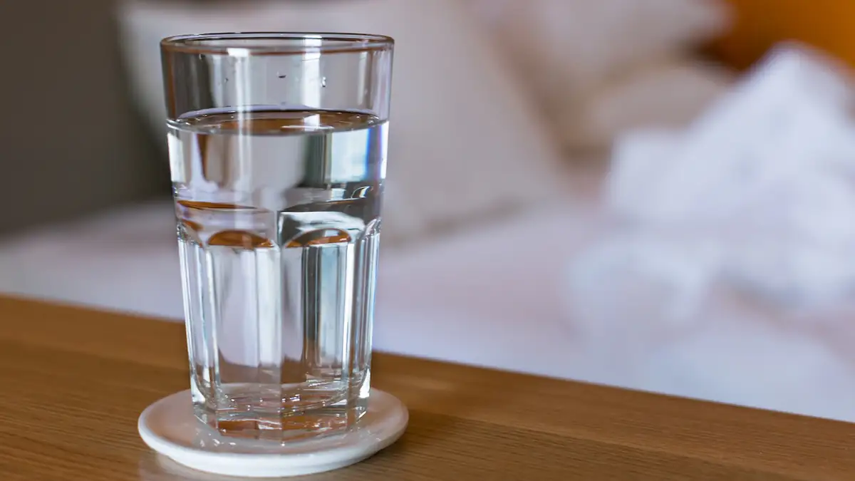 Essen Fasten: Ein Glas Wasser steht neben einem Bett