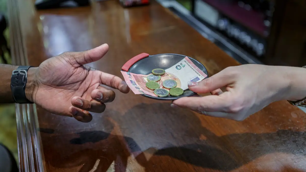 Trinkgeld wird ein einer Schale über den Tisch gereicht