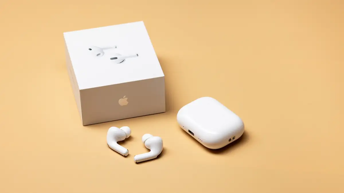 AirPods Pro 3 liegen neben ihrem Case und dem Karton vor beigem Hintergrund
