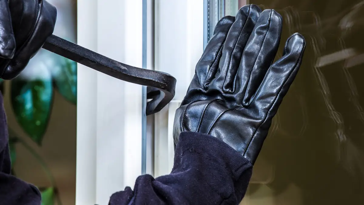 Einbrecher mit Handschuhen und Stemmeisen versucht, eine Tür aufzubrechen