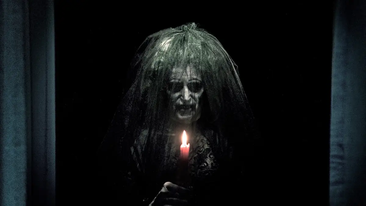 Szene aus dem Film „Insidious“, in der eine gruselige Gestalt eine Kerze hochhält