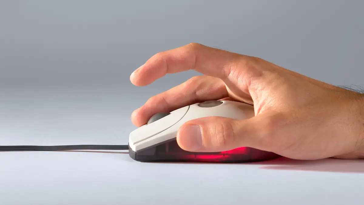 PC-Maus von der Seite in Benutzung, indem eine Hand auf ihr liegt