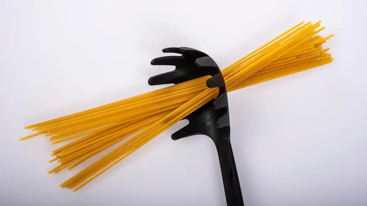 Eine Handvoll Spaghetti wurden durch das Loch eines Spaghetti-Löffels gesteckt