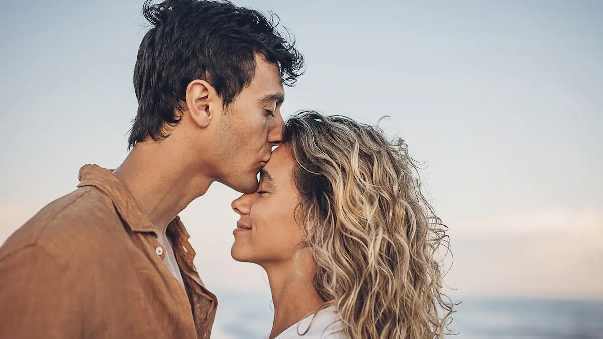 Artikel über Boyfriend Symbolbild: Junger Mann küsst seine Partnerin liebevoll auf die Stirn