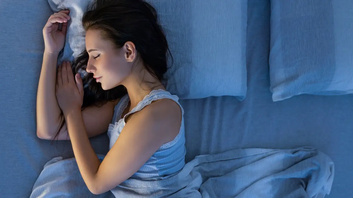 Schlafposition: Junge Frau schläft im Bett auf der Seite