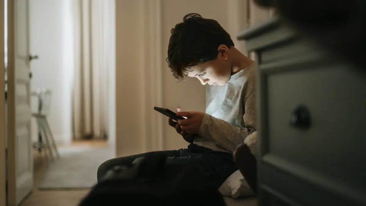 LKA warnt vor Taschengeld-Treffen: Junge schaut vornübergebeugt auf seine Smartphone