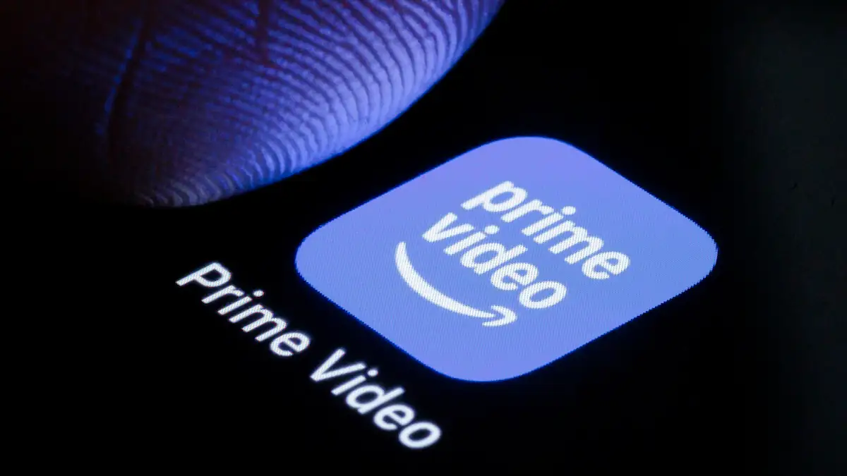 App-Logo von Amazon Prime Video auf einem Smartphone, über dem ein Finger schwebt