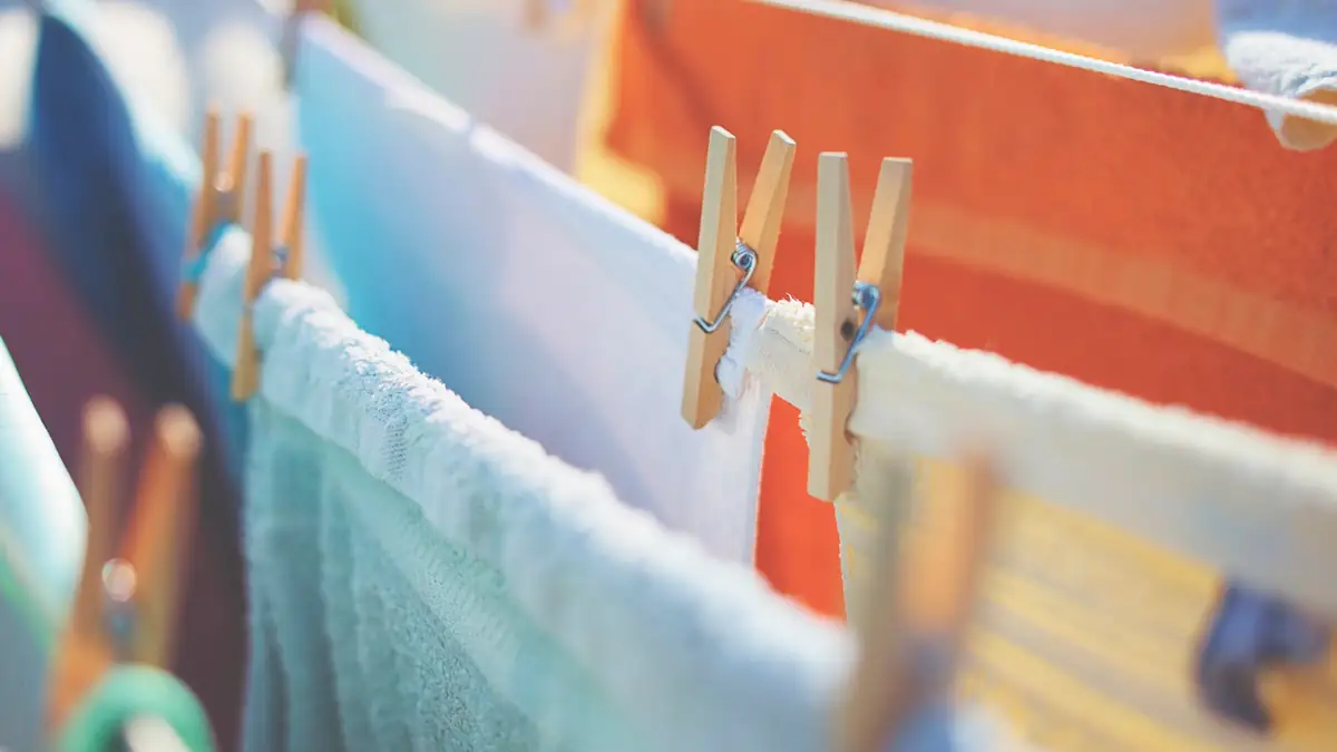 Bunte Wäsche trocknet auf einer Wäscheleine und wird mit Klammern gehalten