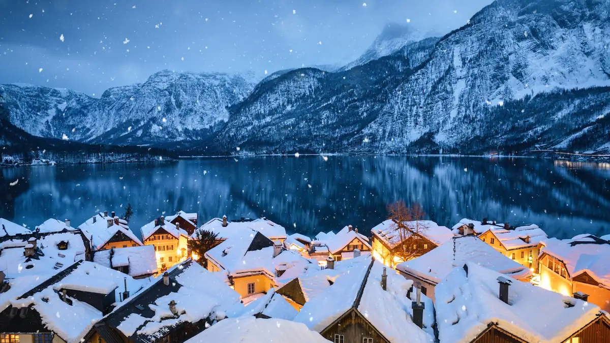 Weiße Weihnachten: Festlich erleuchtetes Dorf an einem See bei sanftem Schneefall