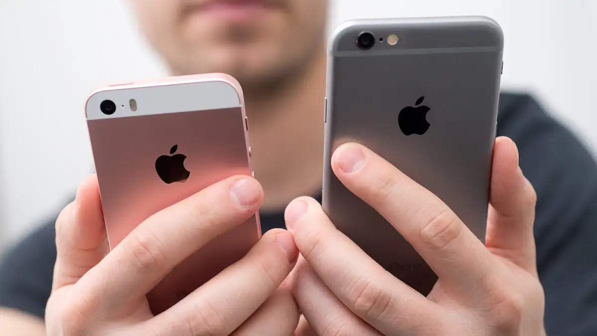 Jemand hält ein iPhone SE (1. Generation) und ein iPhone 6 zum Vergleich nebeneinander