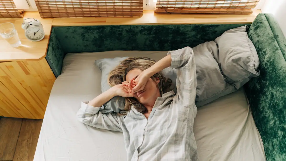 Schlafsand: Frau reibt sich nach dem Aufwachen die Augen