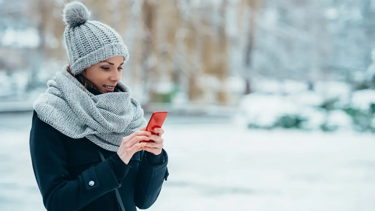 Junge Frau mit Smartphone im Winter