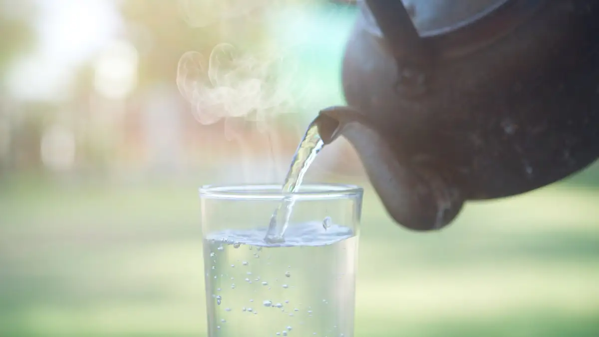 Heißes Wasser wird aus einer Kanne in ein Glas gegossen