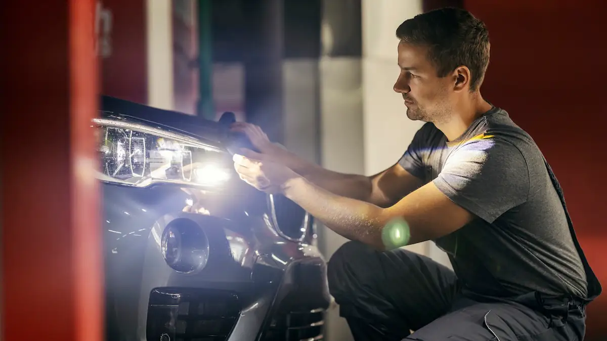 ADAC vergleicht Kosten für Auto-Reparatur: Mann repariert Vorderseite eines Autos