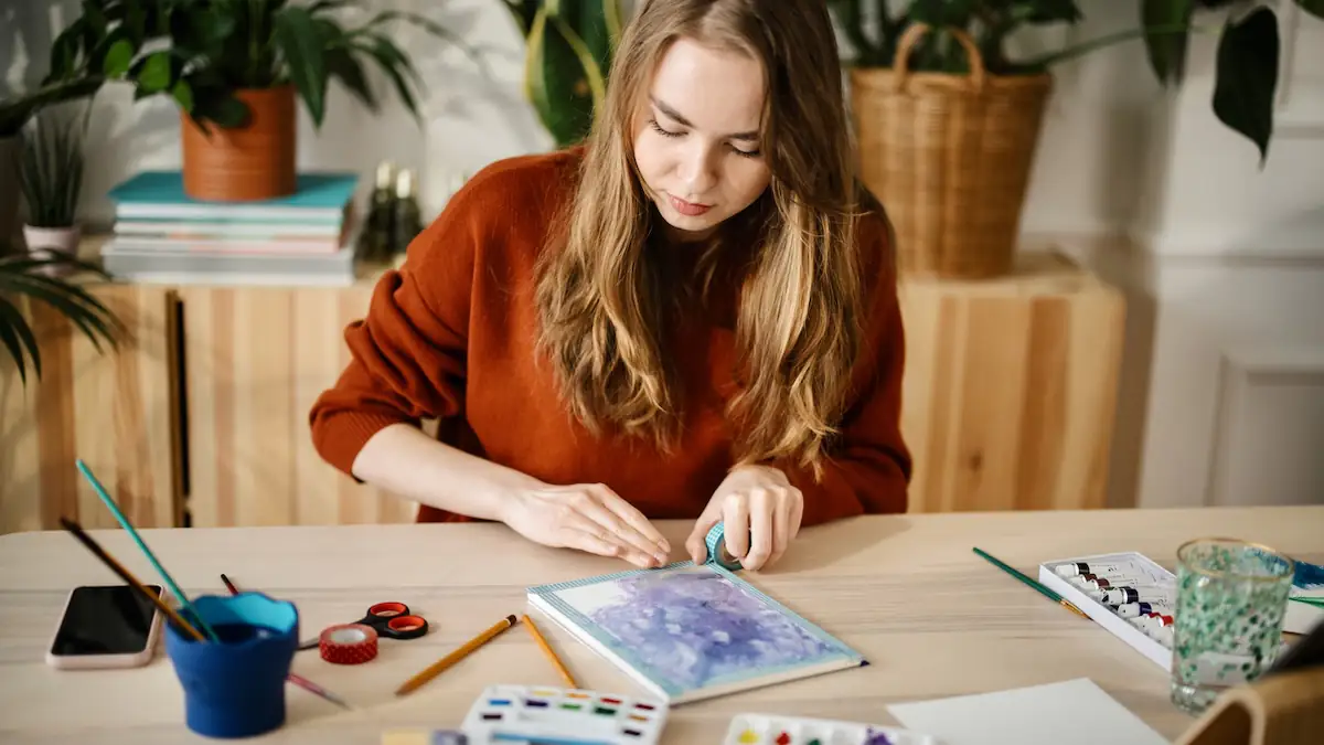 Analog Bag: Junge Frau malt ein Bild, während ihr Smartphone ausgeschaltet ist