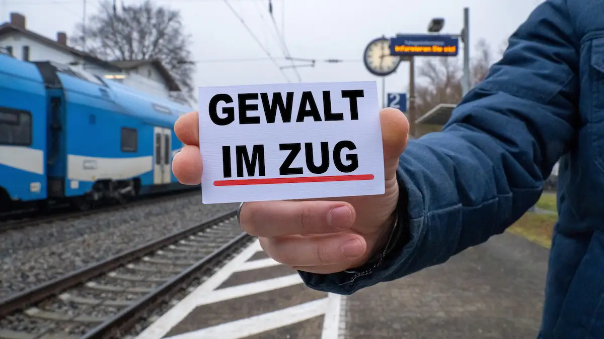 Zugbegleiter nach Angriff verstorben:: Jemand hält am Bahnhof ein Schild mit der Aufschrift „Gewalt im Zug“