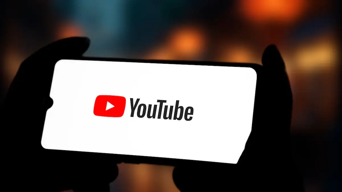 Jemand hält ein Smartphone mit YouTube-Logo in der Hand