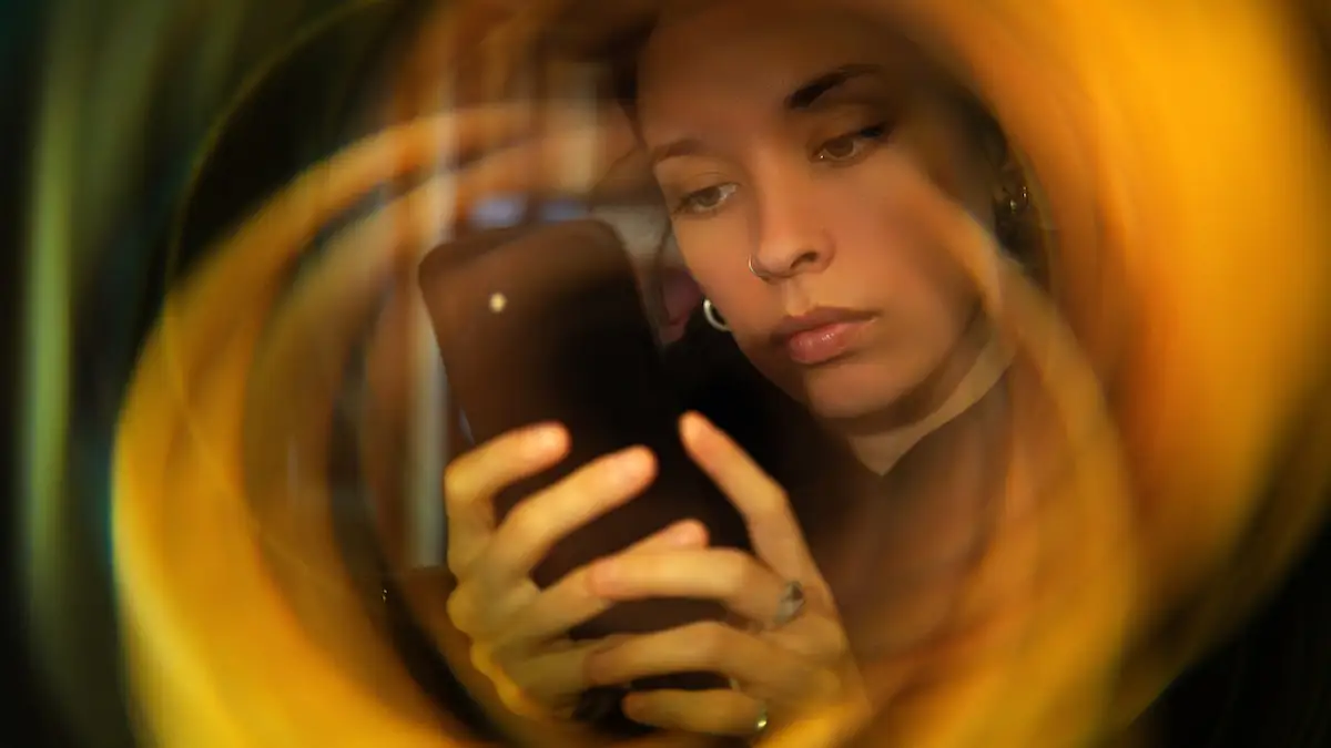 Doomscrolling: Frau starrt in einem Wirbel auf ihr Handy