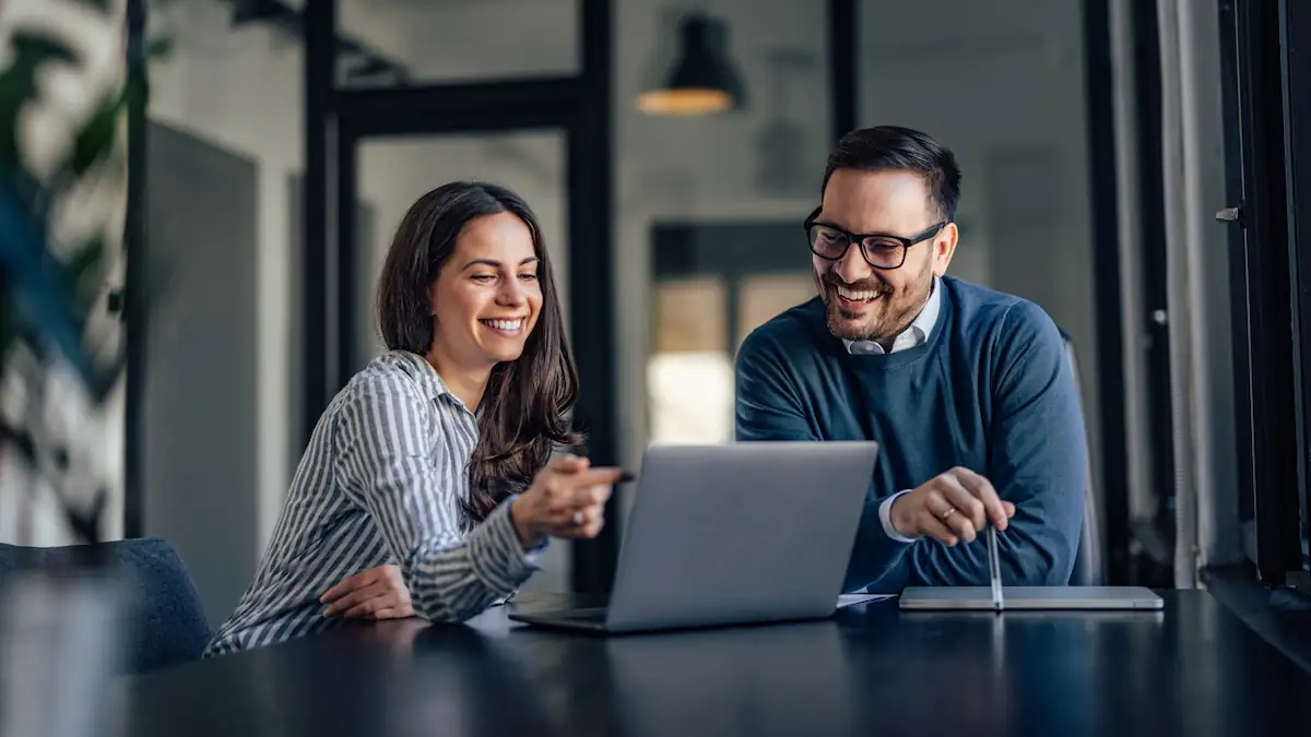 Mann und Frau sitzen im Job nebeneinander an einem Laptop