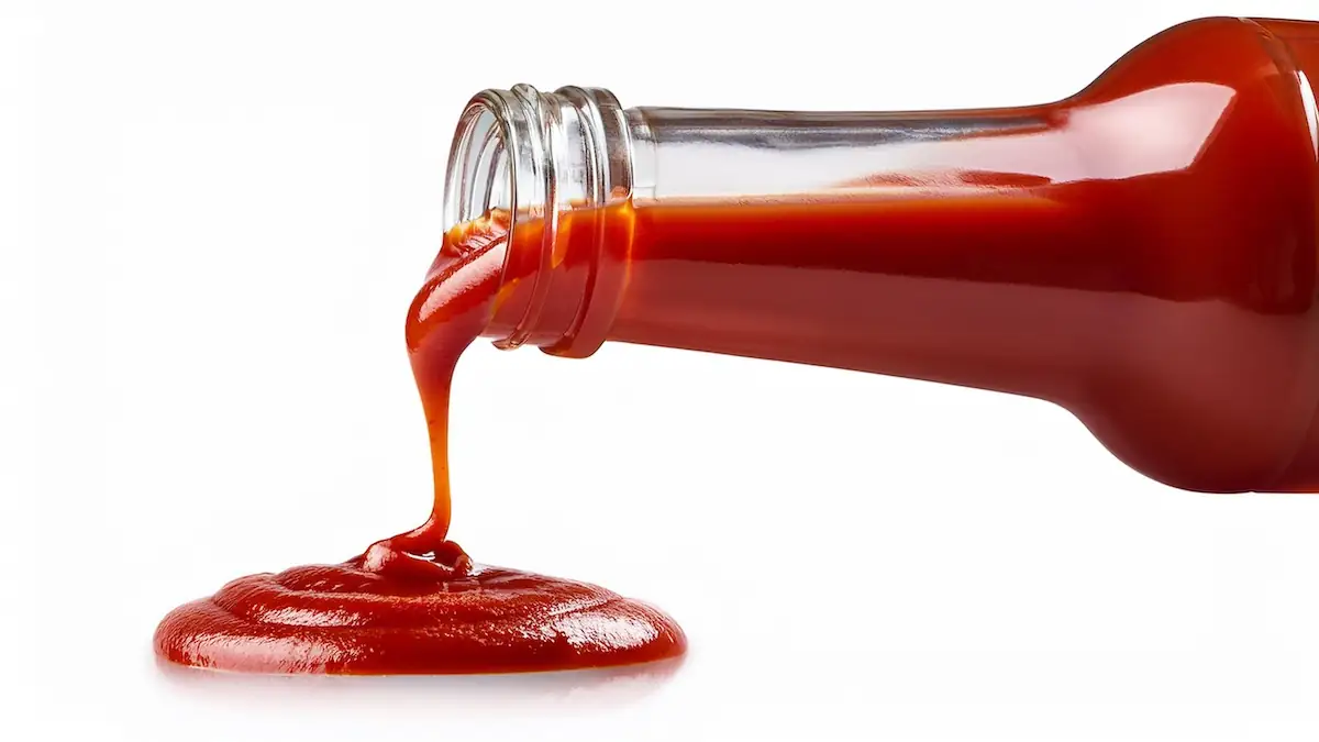 Ketchup läuft aus einer gläsernen Flasche