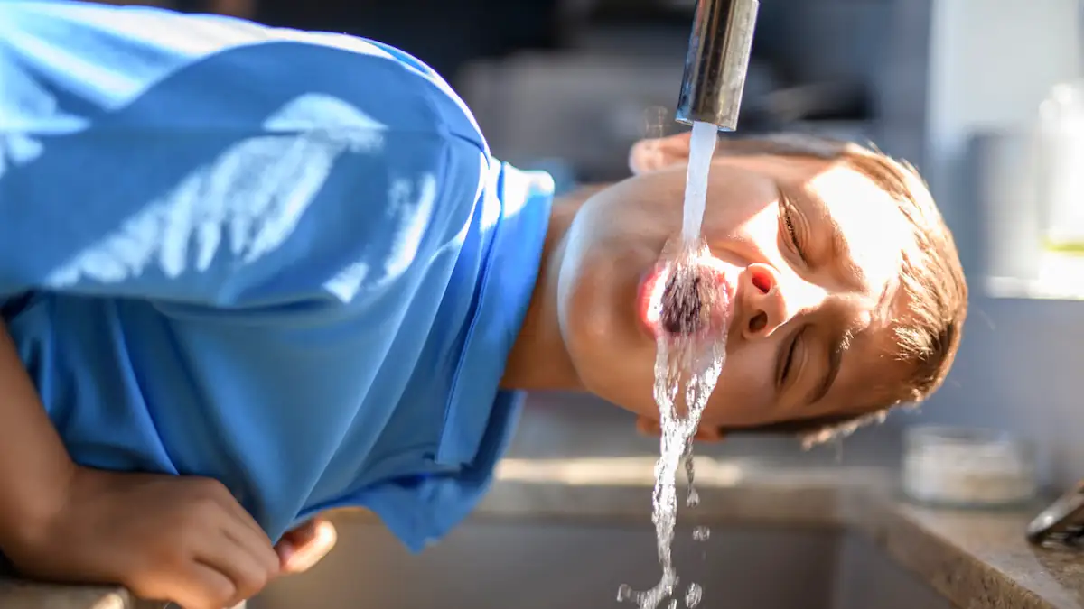 Junge trinkt Leitungswasser aus dem Wasserhahn