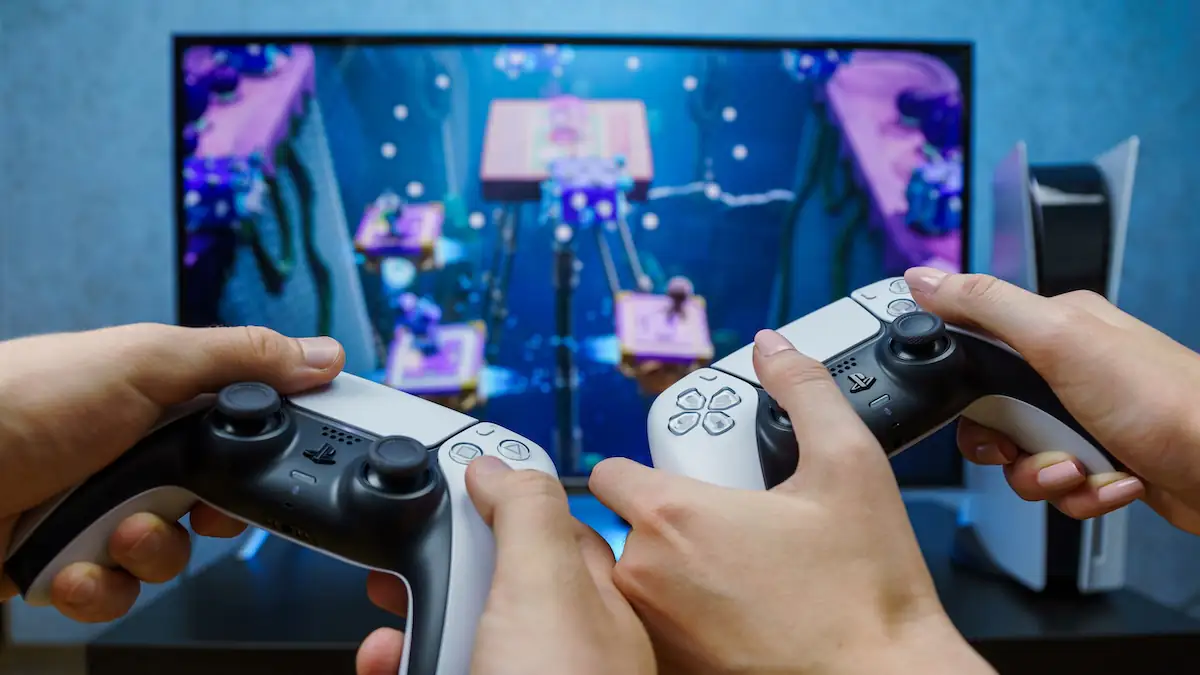 Zwei Personen spielen zusammen mit weißen PlayStation-Controllern