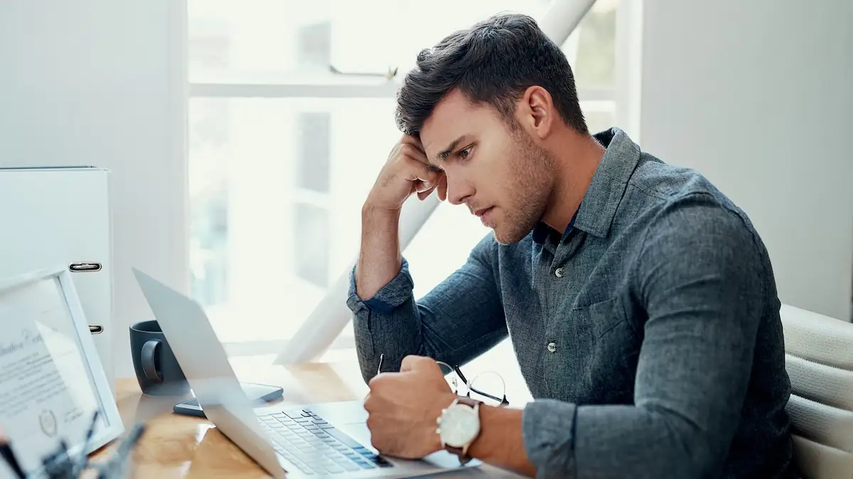 SEO Poisoning Symbolbild: Mann sitzt entmutigt vor seinem Laptop