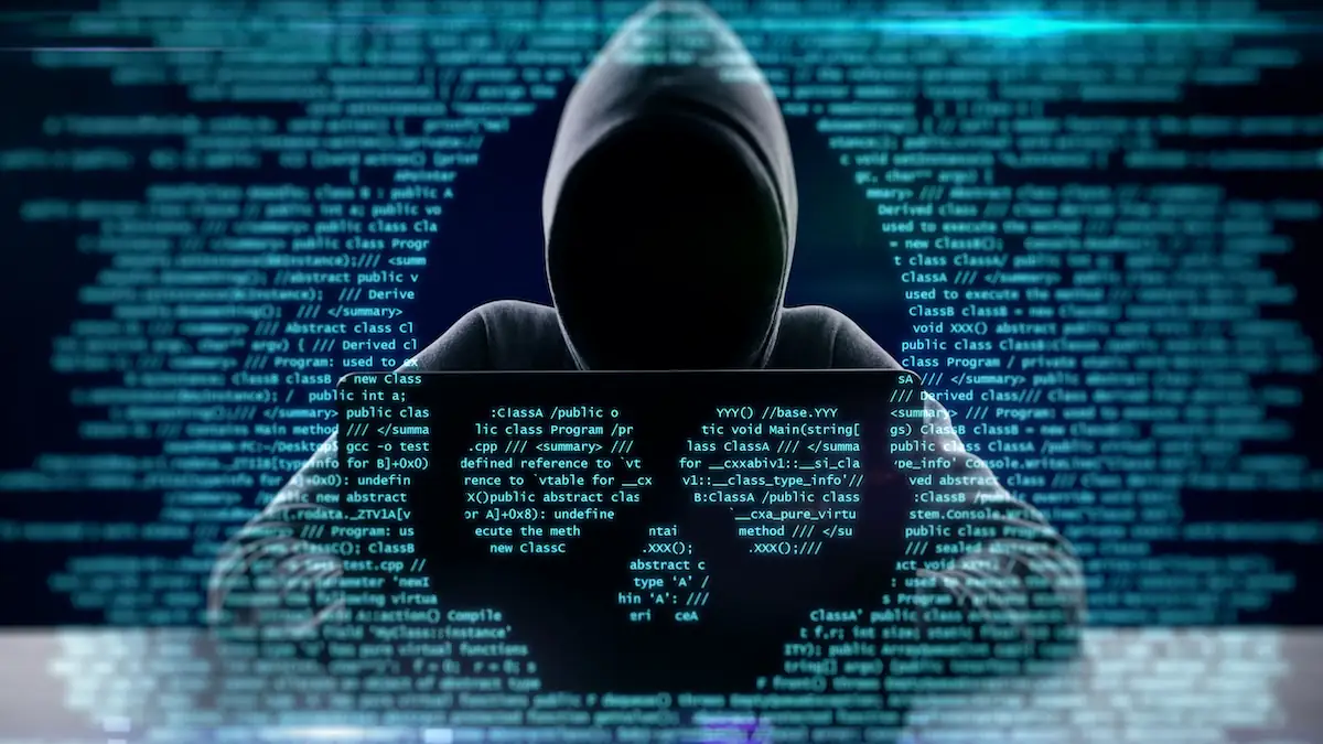 SEO Poisoning Symbolbild: Düstere Kapuzengestallt sitzt vor einem Laptop