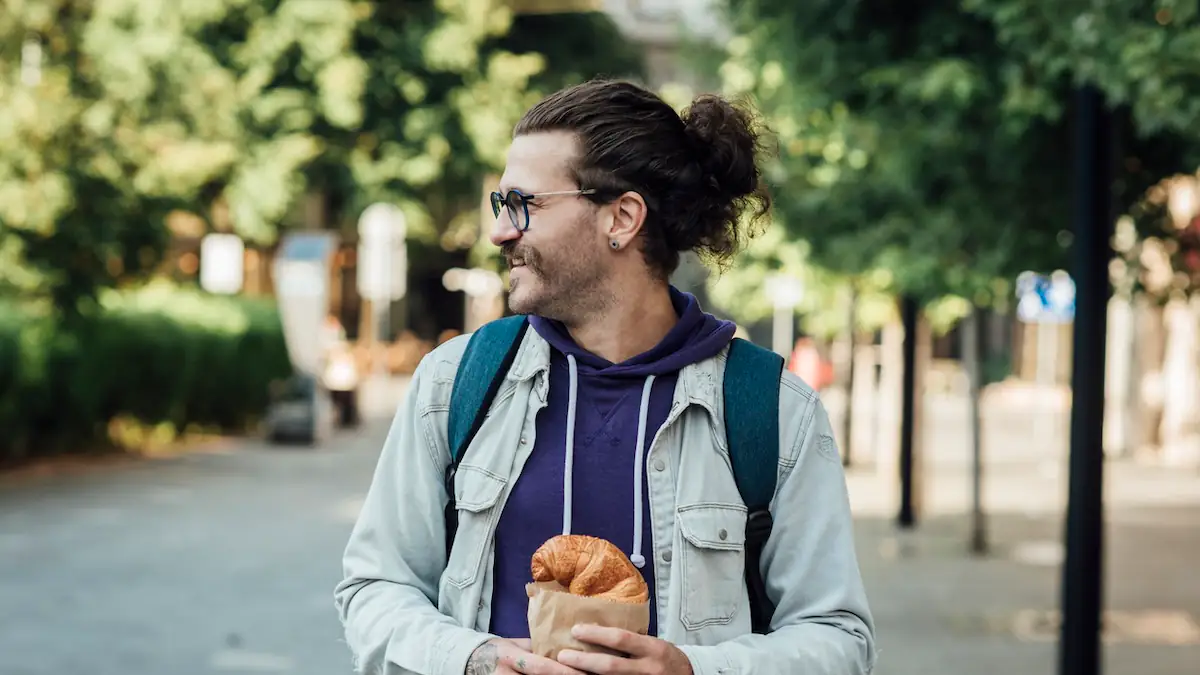 Junger Mann isst ein Croissant