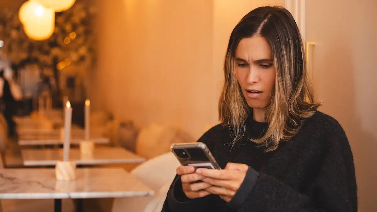 Frau schaut irritiert auf ihr Smartphone