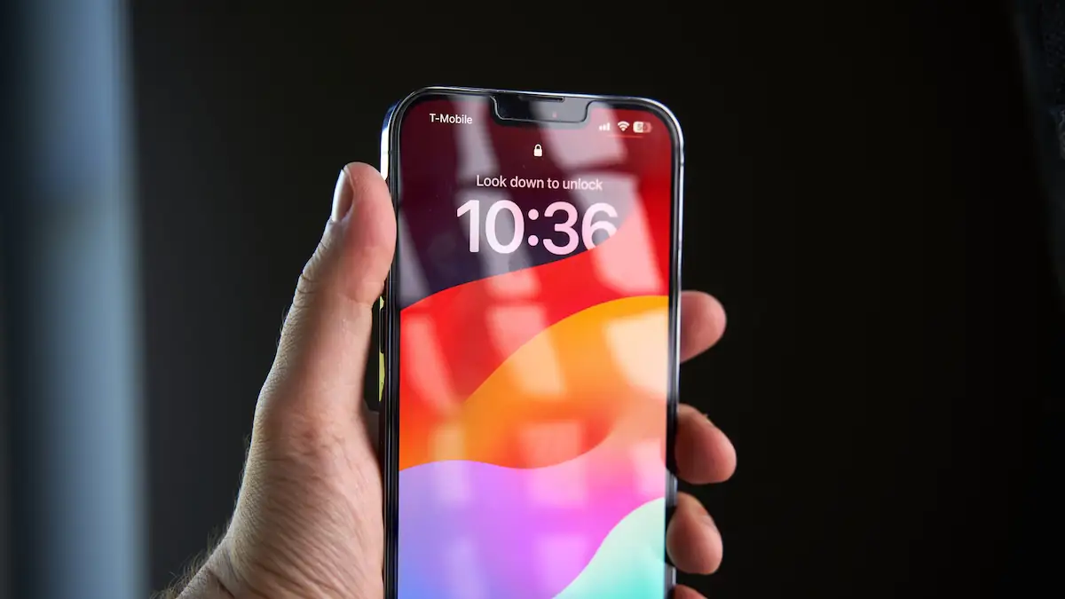 iPhone wird vor dunklem Hintergrund hochgehalten