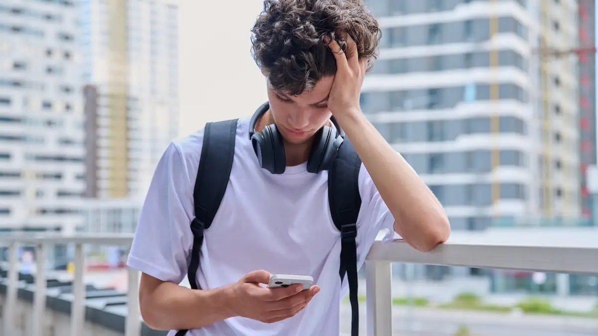 Dating-Trend Paperclipping: Junger Mann schaut traurig nach unten auf sein Smartphone