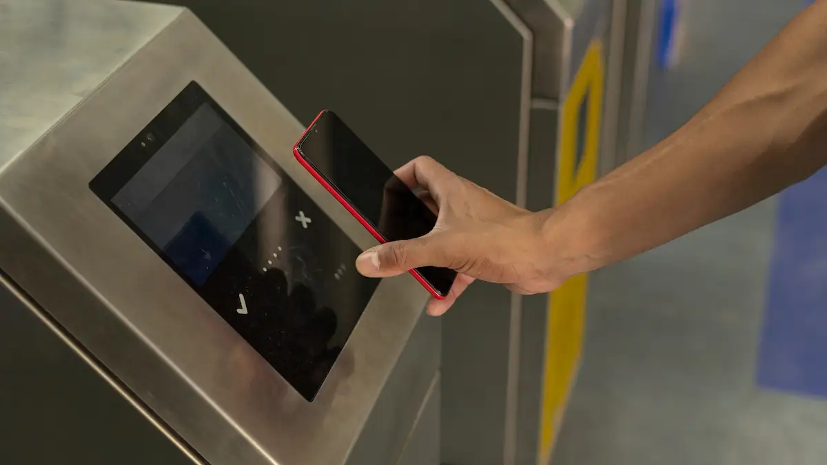 Jemand hält ein iPhone zum Bezahlen an ein Terminal