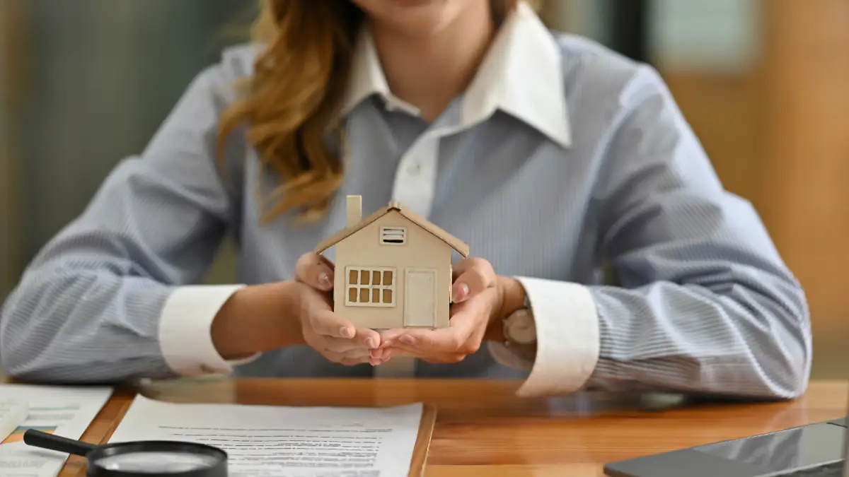 Symbolbild Mietrecht: Frau hält Miniaturhaus in ihren Händen
