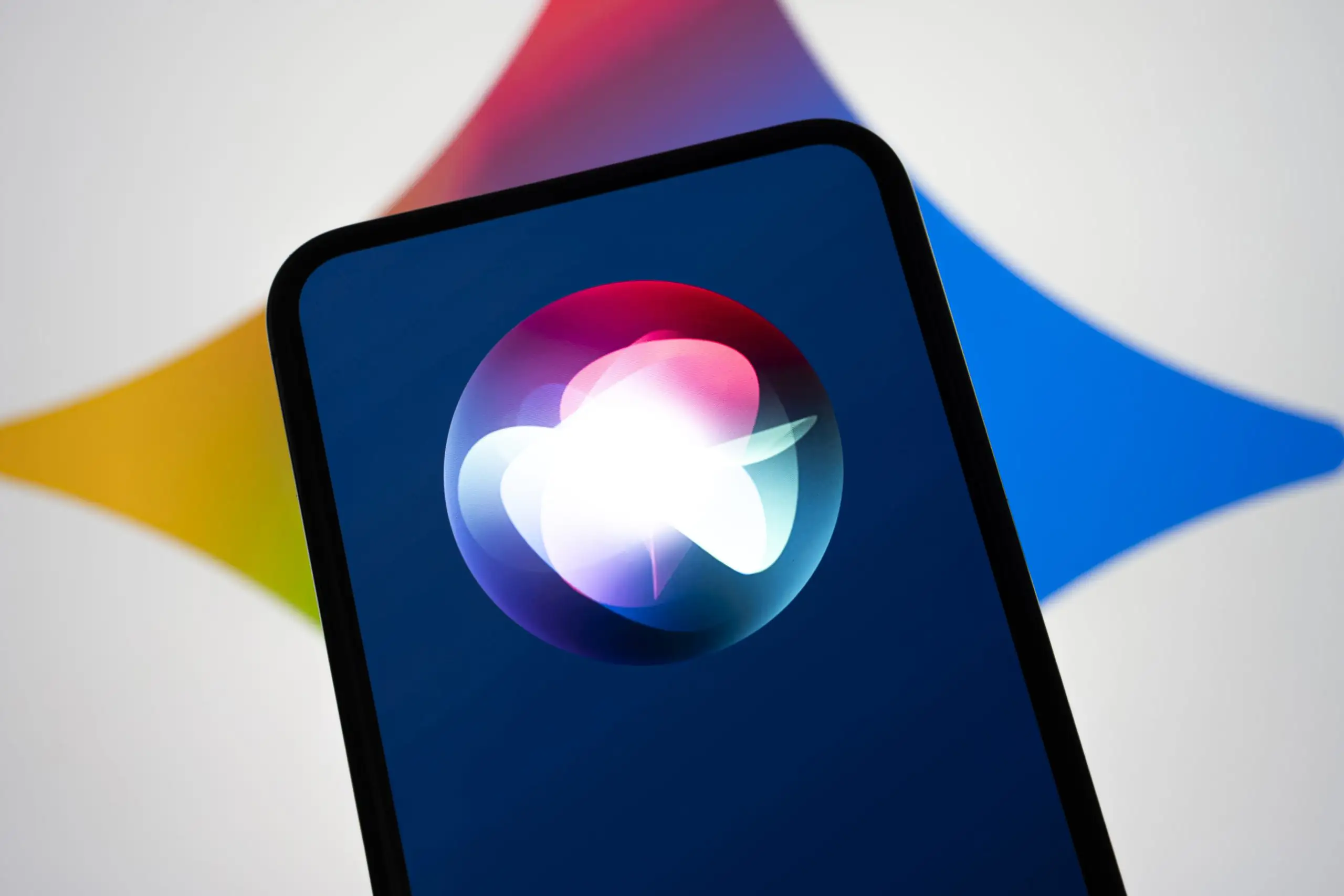 Apple Siri auf iPhone, im Hintergrund Logo von Gemini