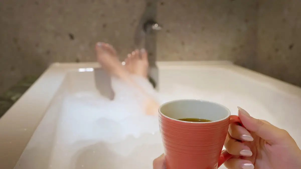 Gemütliches Baden: Jemand nimmt mit einer Tasse Kaffee in der Hand ein Schaumbad