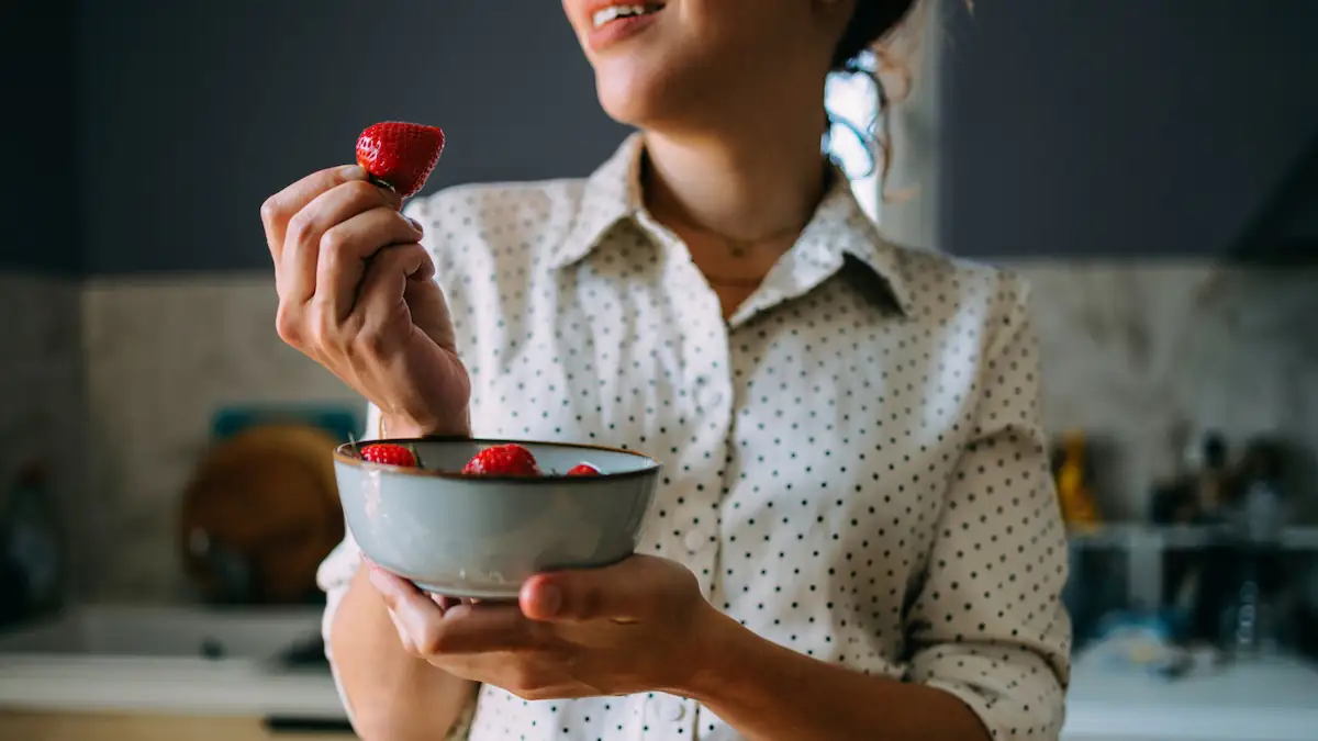 Junge Frau hält eine Schüssel mit Erdbeeren, um sie zu essen